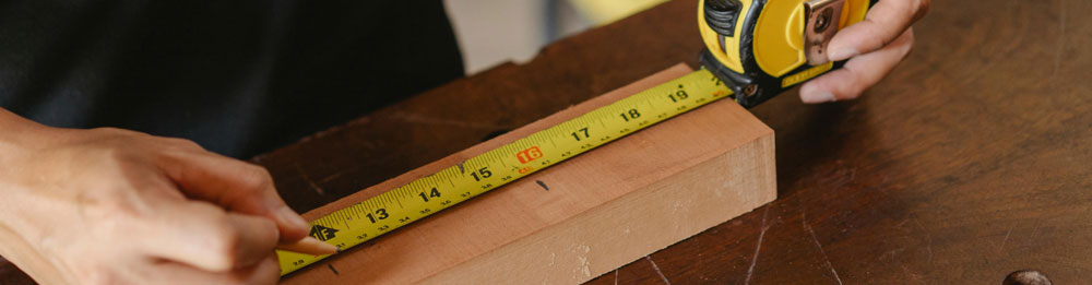 A person measuring a wooden plank for a DIY project
